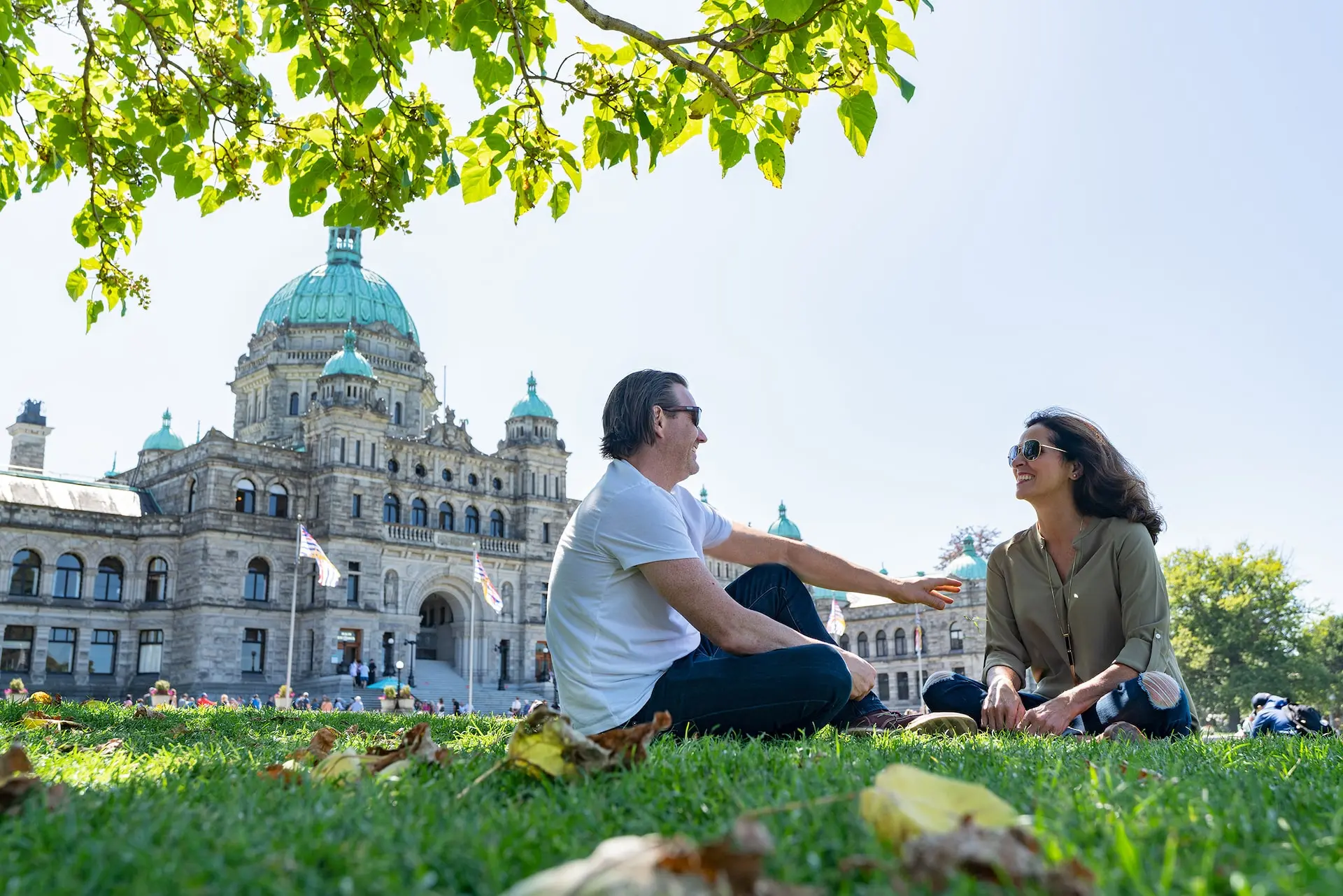 A couple sitting on the lawn outside BC Legislature in Victoria, BC