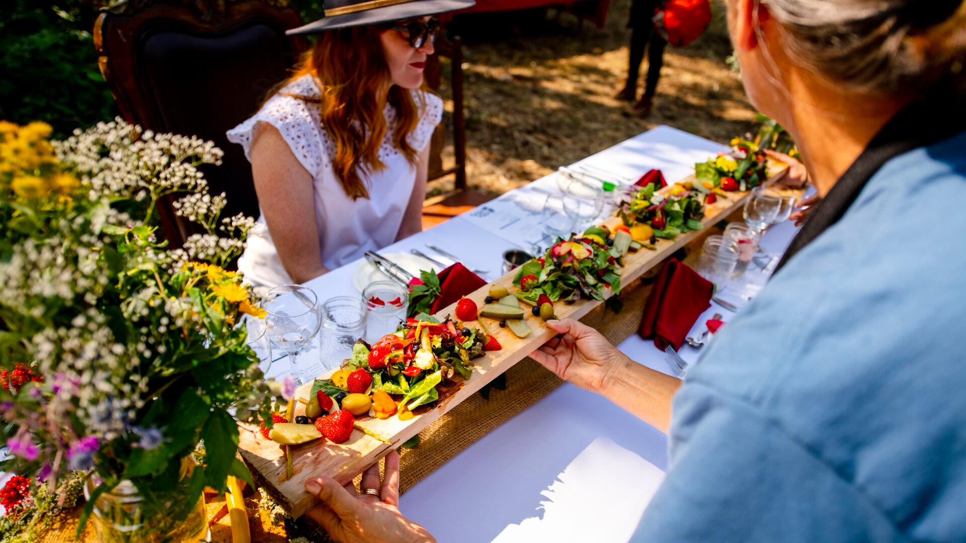 A woman is presented with a tray of fresh fruits and vegetables 