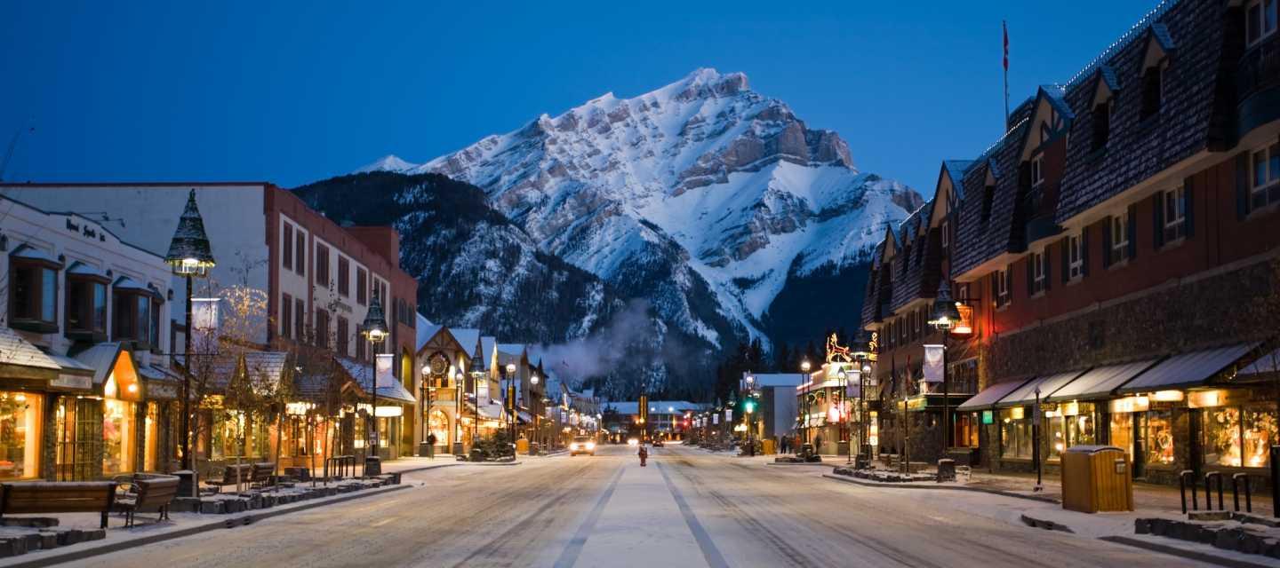 Banff, at night, with a view down a main road toward the snow-capped mountains