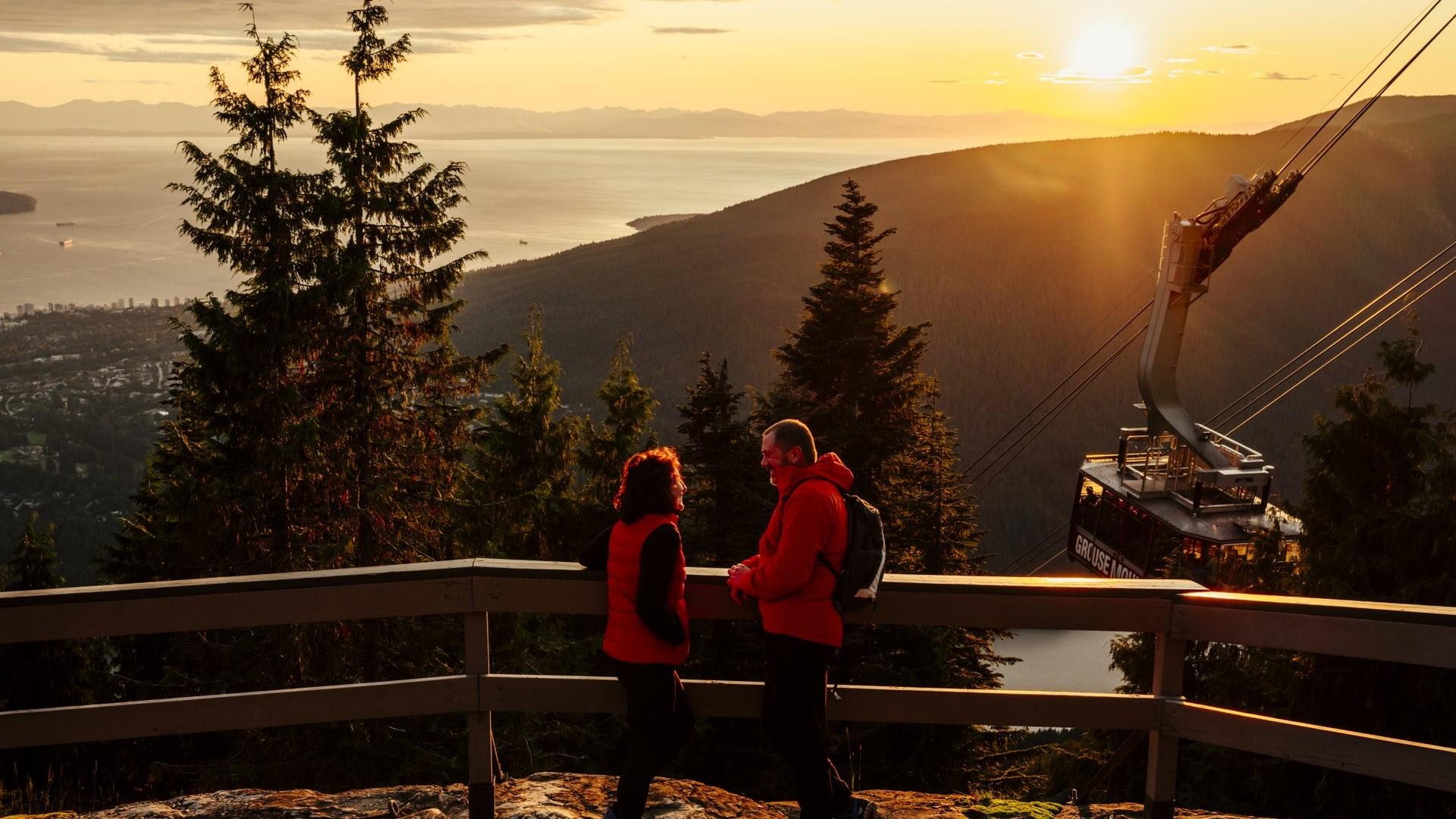 Two people chat on an observation deck as a gondola passes by