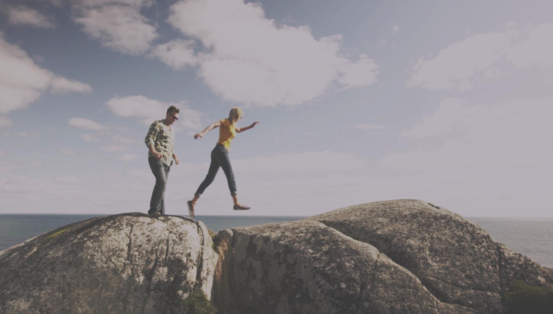 Two people jumping on some large rocks