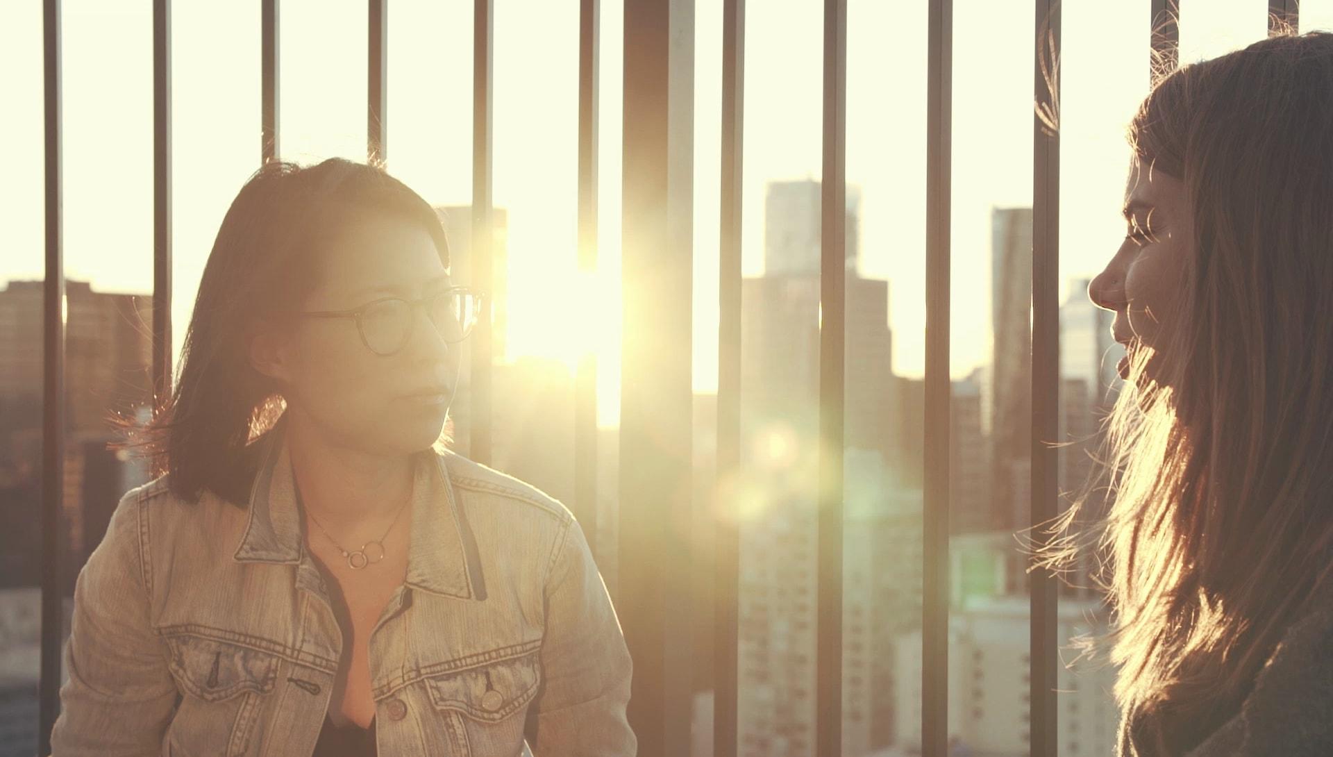 Two people talking on a sunny bridge