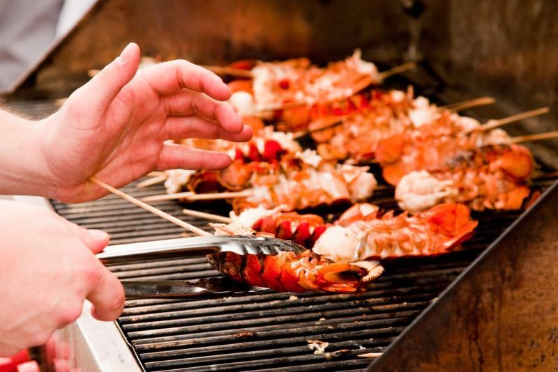 A person barbecuing lobster tails