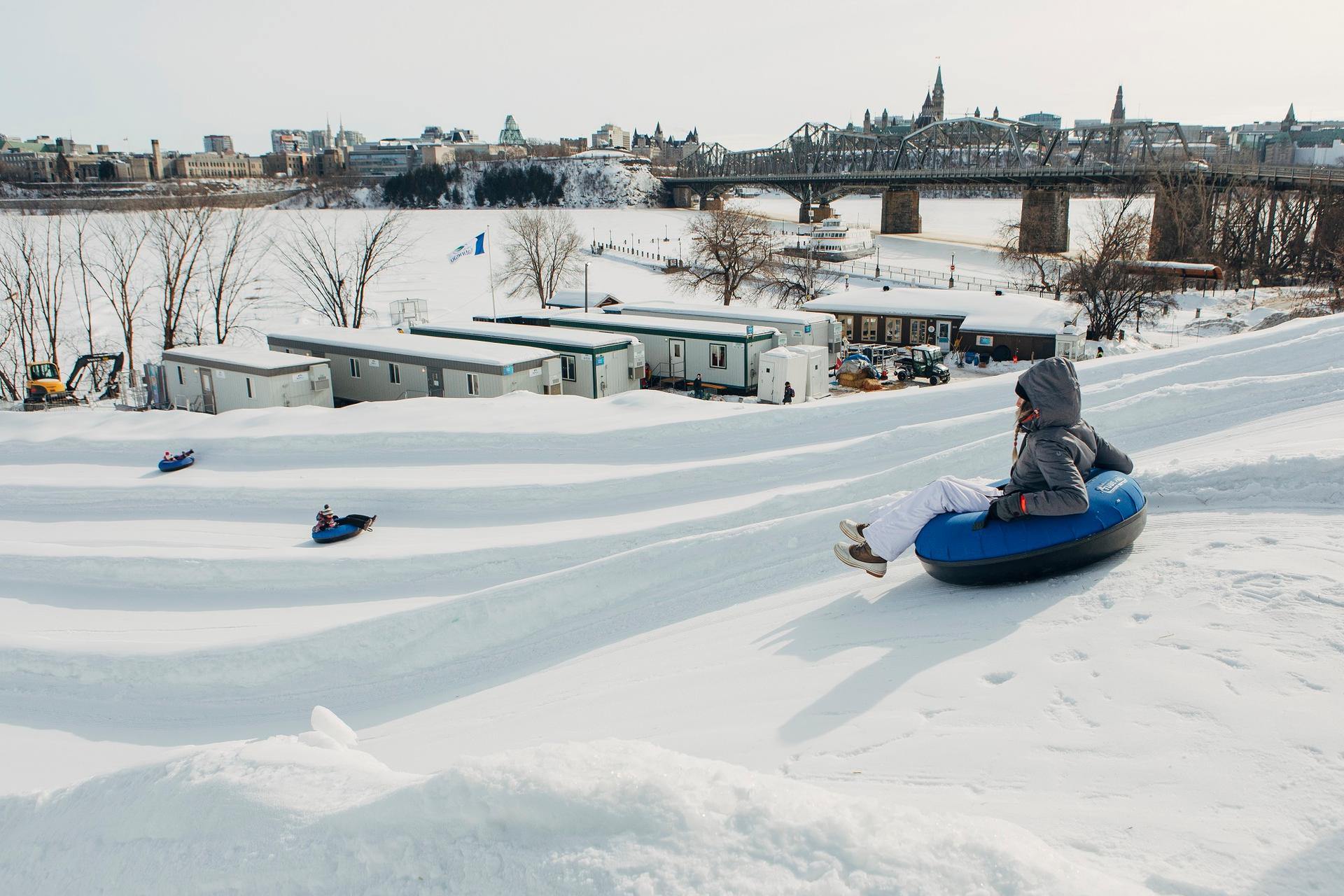 A child rides a tube down a snowy hill near the Ottawa river