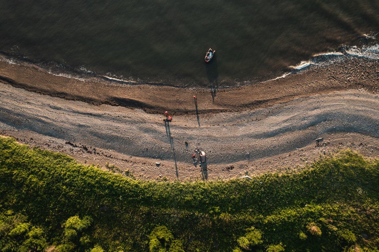 a long road shot from birds eye with two people walking on it and greenery on either side