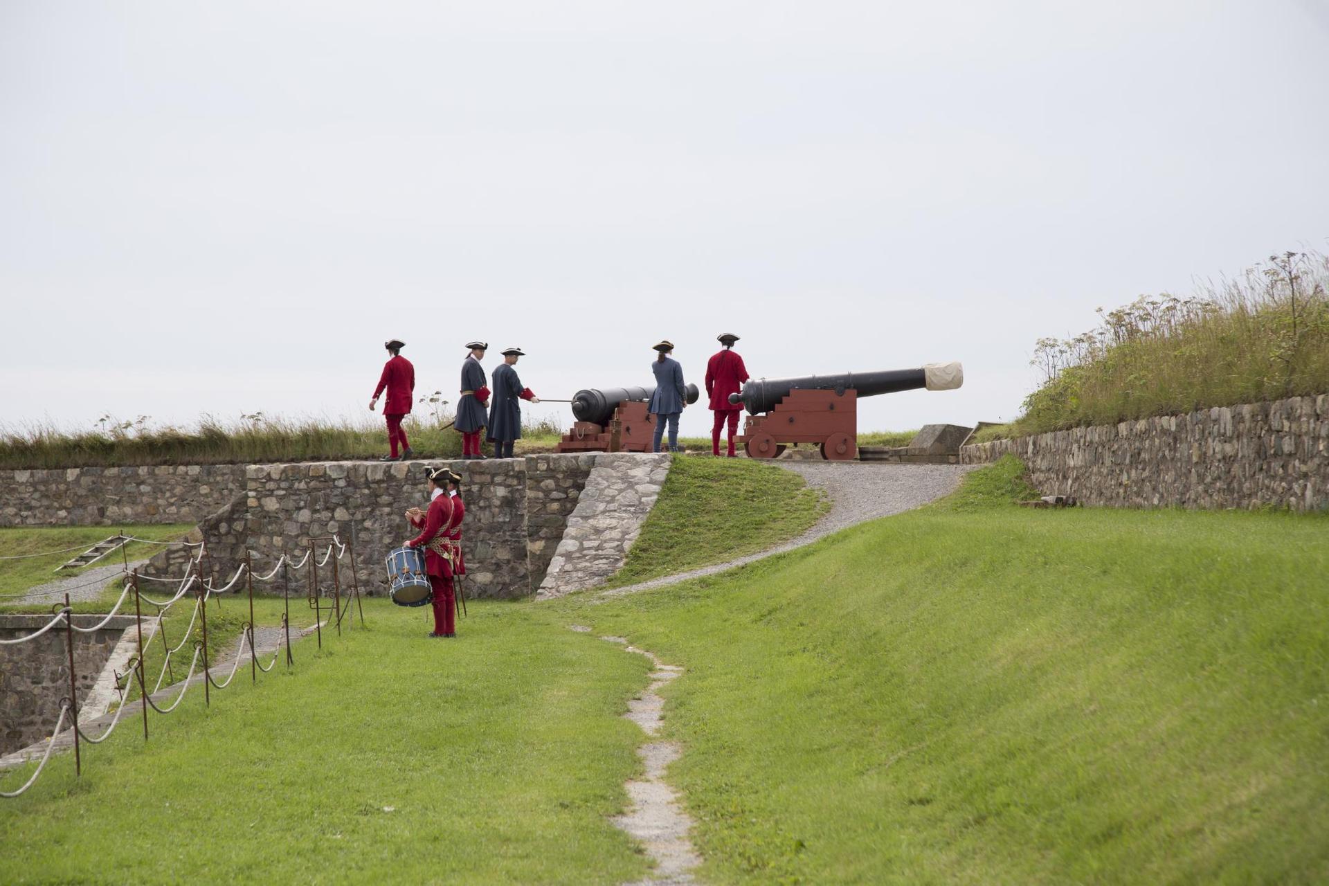 Soldiers atop a grassy area on the fortress with canons 