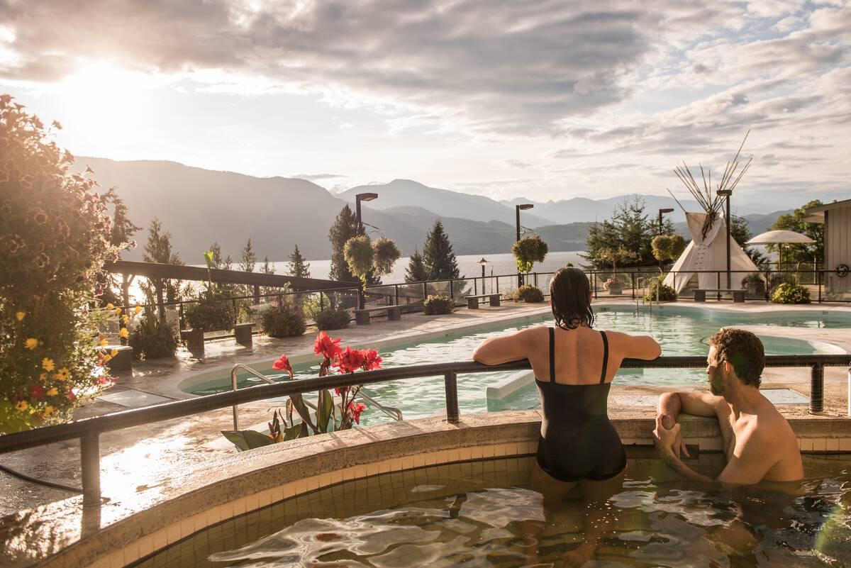 Two bathers enjoy swimming at Ainsworth Hot Springs with a view of Kootenay Lake.