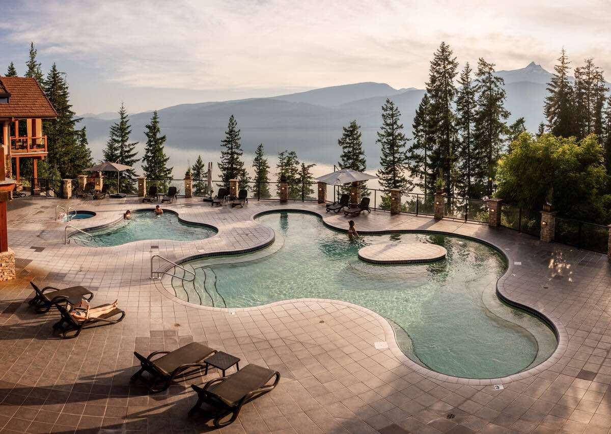 A view of the pools at Halcyon Hot Springs Resort, with water and mountains in the background