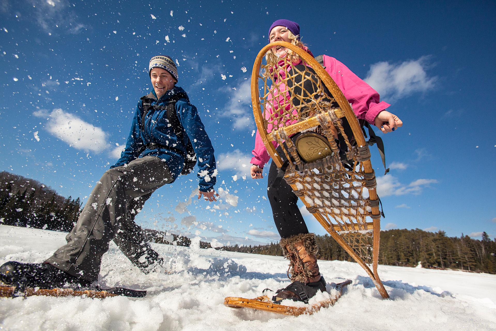 A man and a woman snowshoeing as seen from ground level.