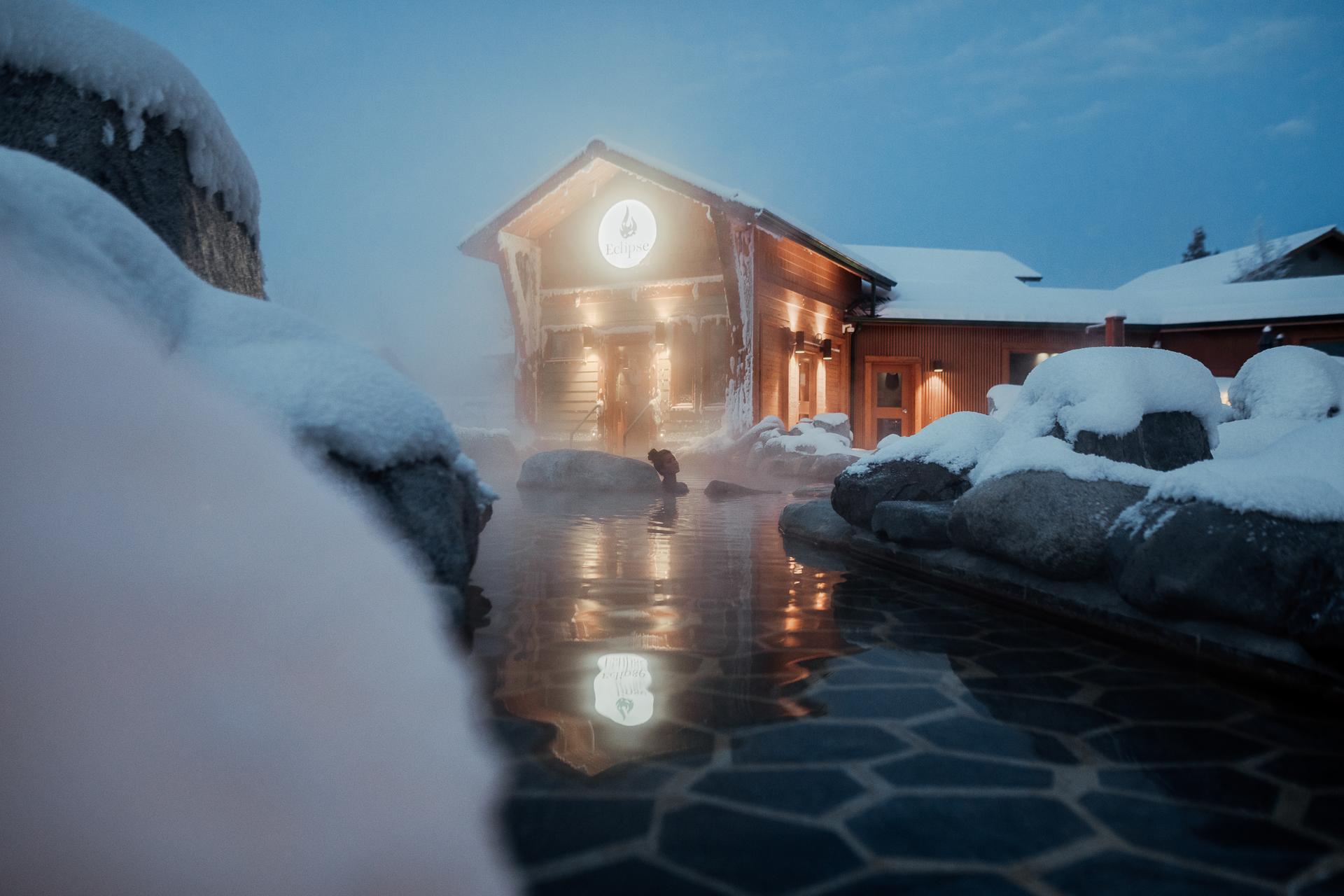 A person relaxing in an outdoor pool at night at the Eclipse Nordic Hot Springs.