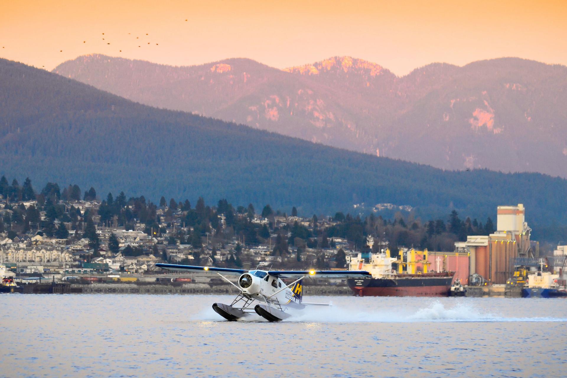 Seaplane landing in water with mountains in the background