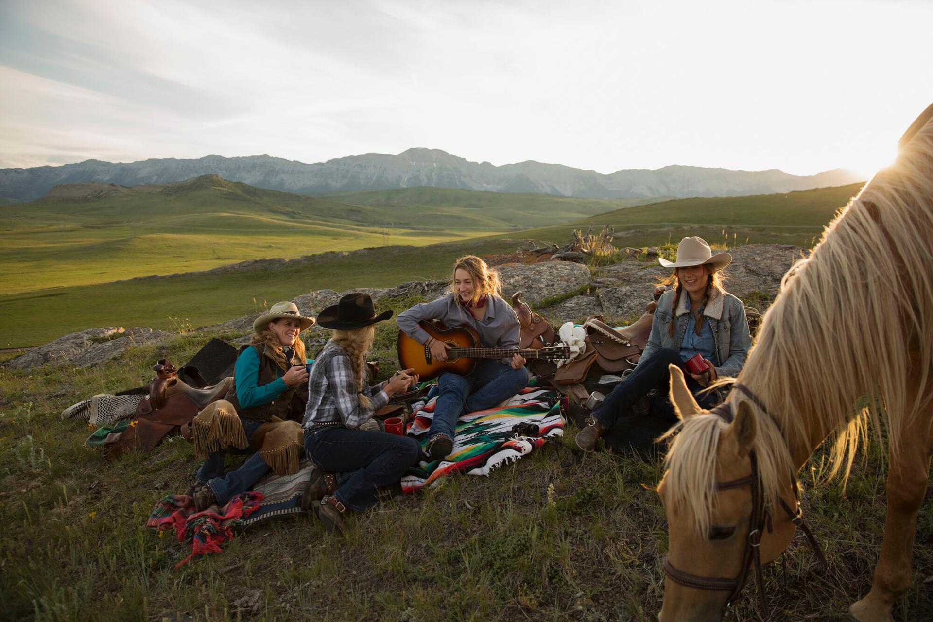 Group relaxing outdoors with guitar and horse in mountain setting