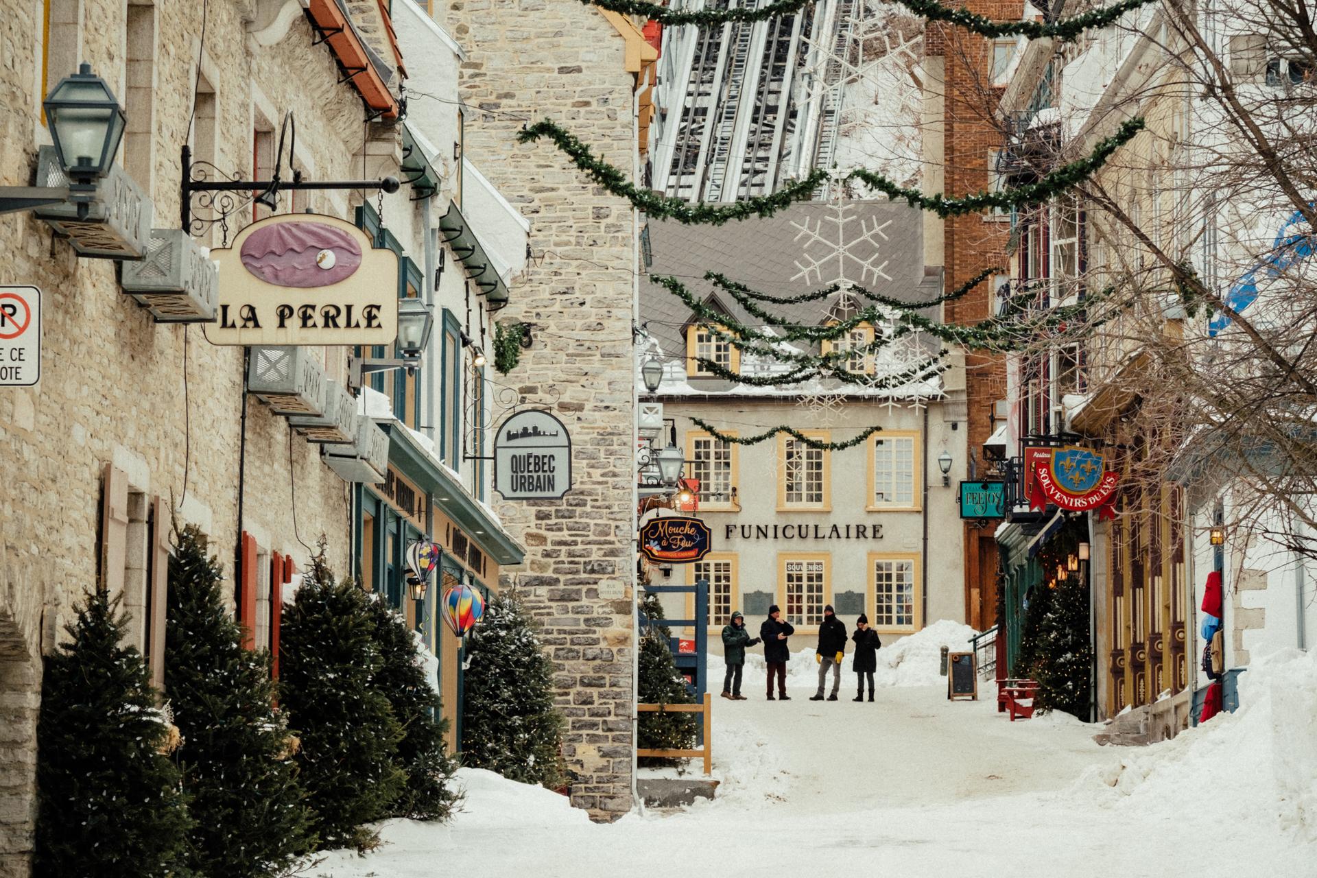 Snow-covered street in Old Québec with stone buildings, festive decorations