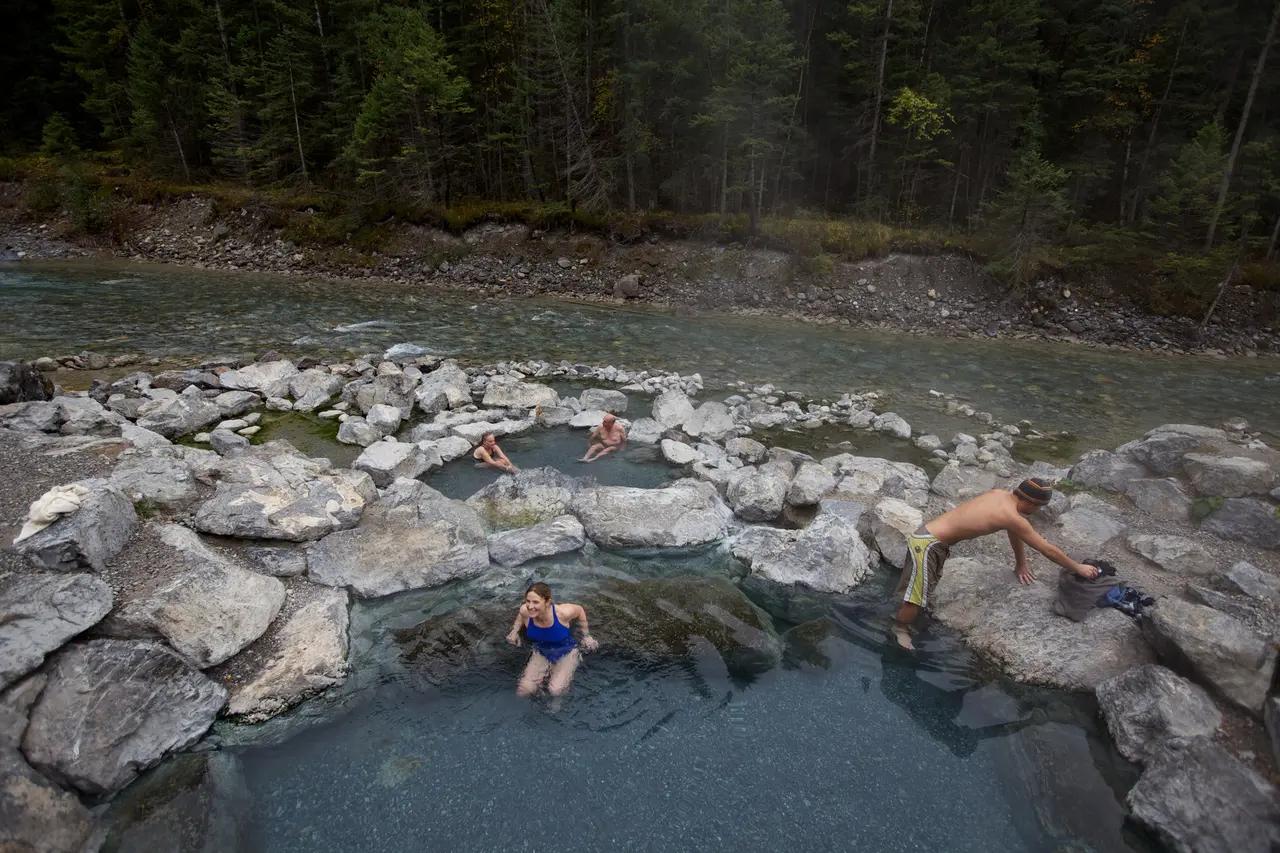 Image of undeveloped pools along the riverbank at Lussier Hot Springs, showing a rustic and minimally managed setting.