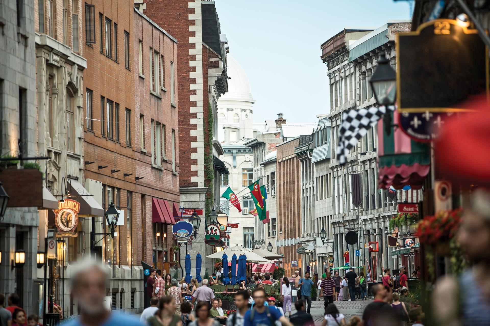 Old Montréal street lined with historic buildings, restaurants, and pedestrians on a bustling day