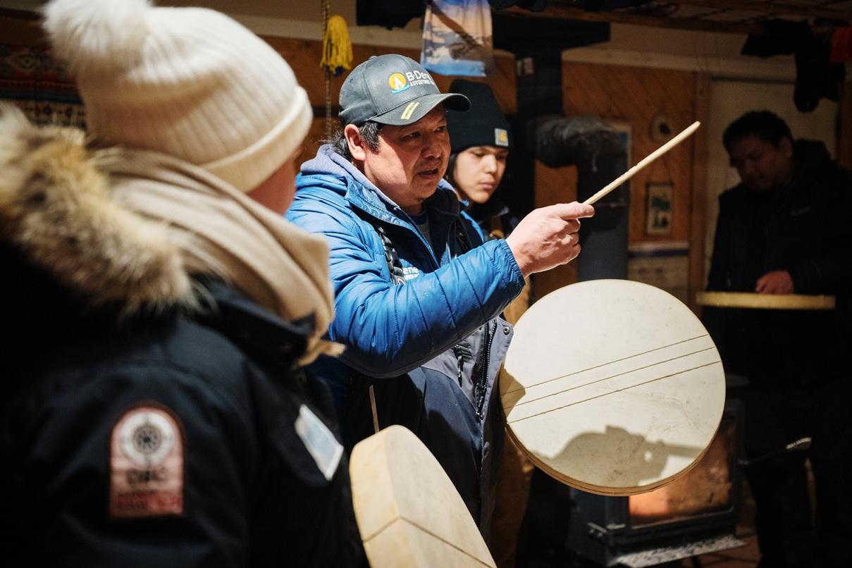 Person demonstrating traditional drumming to a group indoors