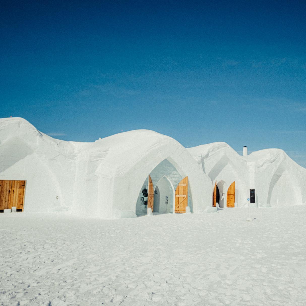 Three igloos with brown doors on a sunny day