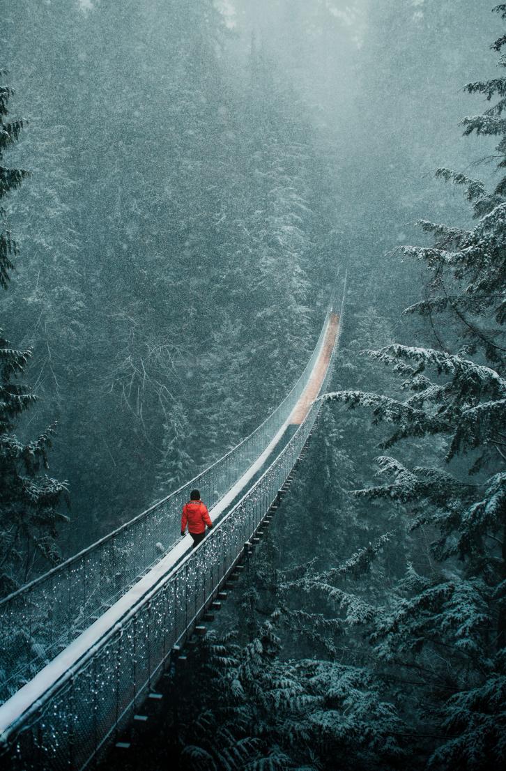 Person walking across Capilano Suspension Bridge in the snow at Capilano Suspension Bridge Park.