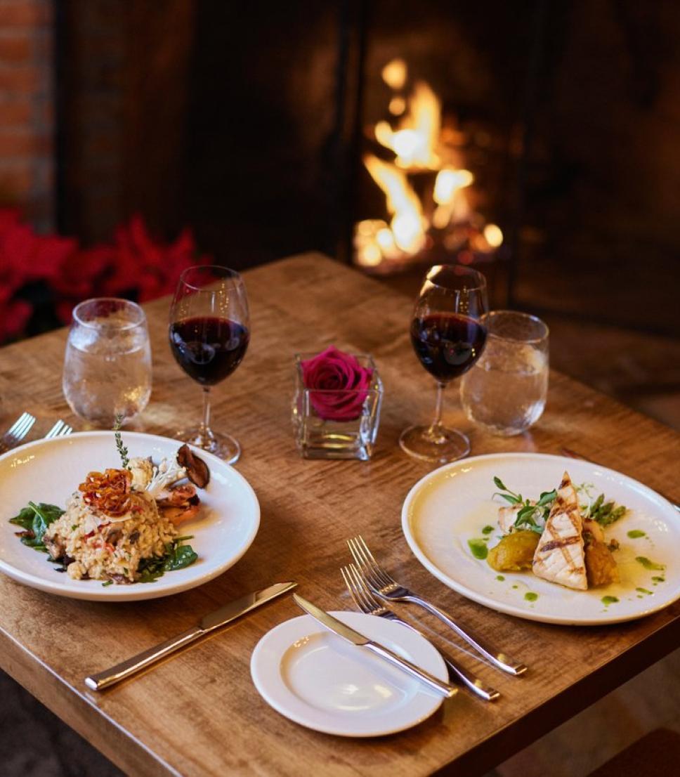 A cozy table set for two with gourmet dishes and red wine