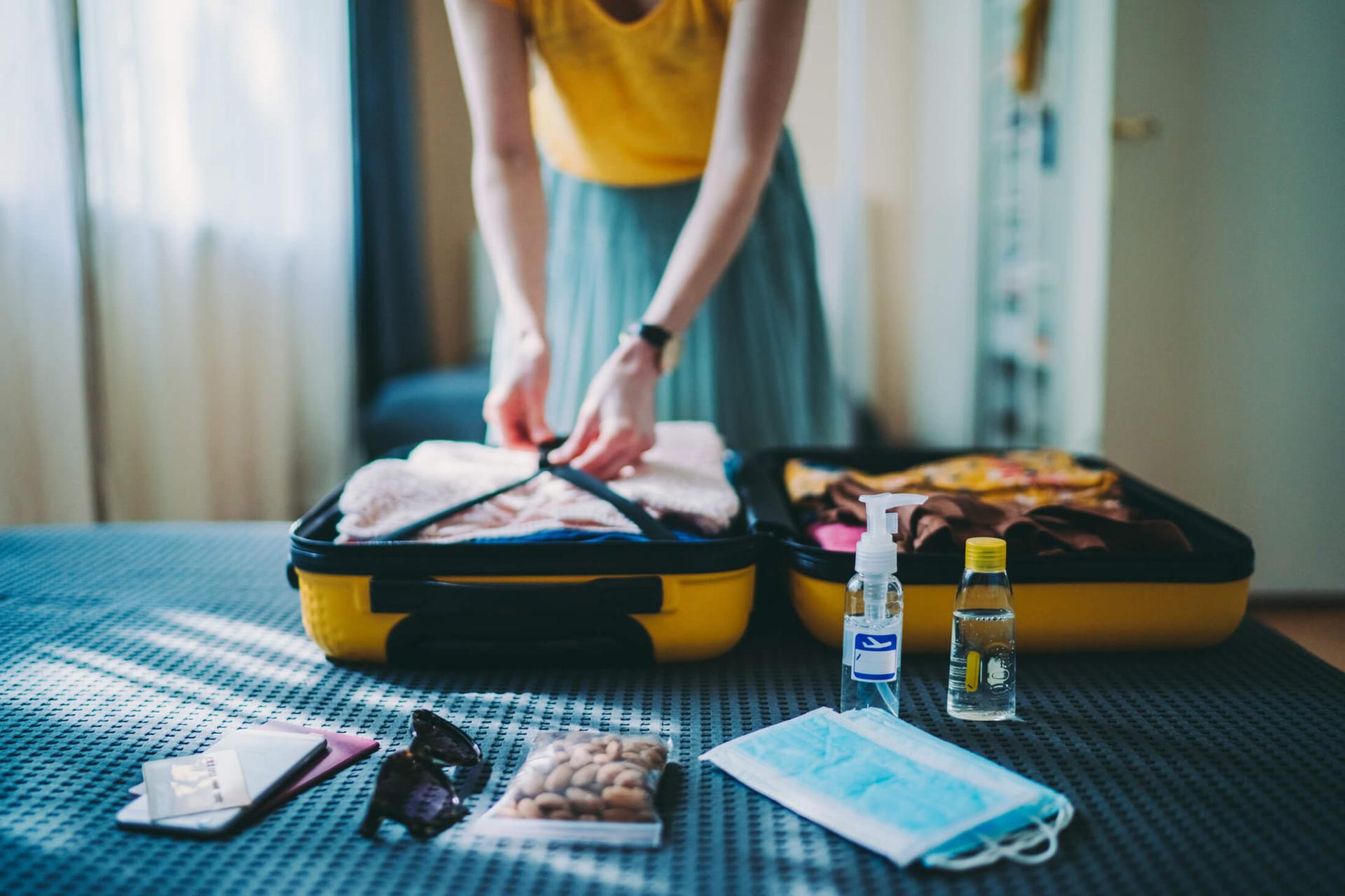 A traveler packing their bag on their bed