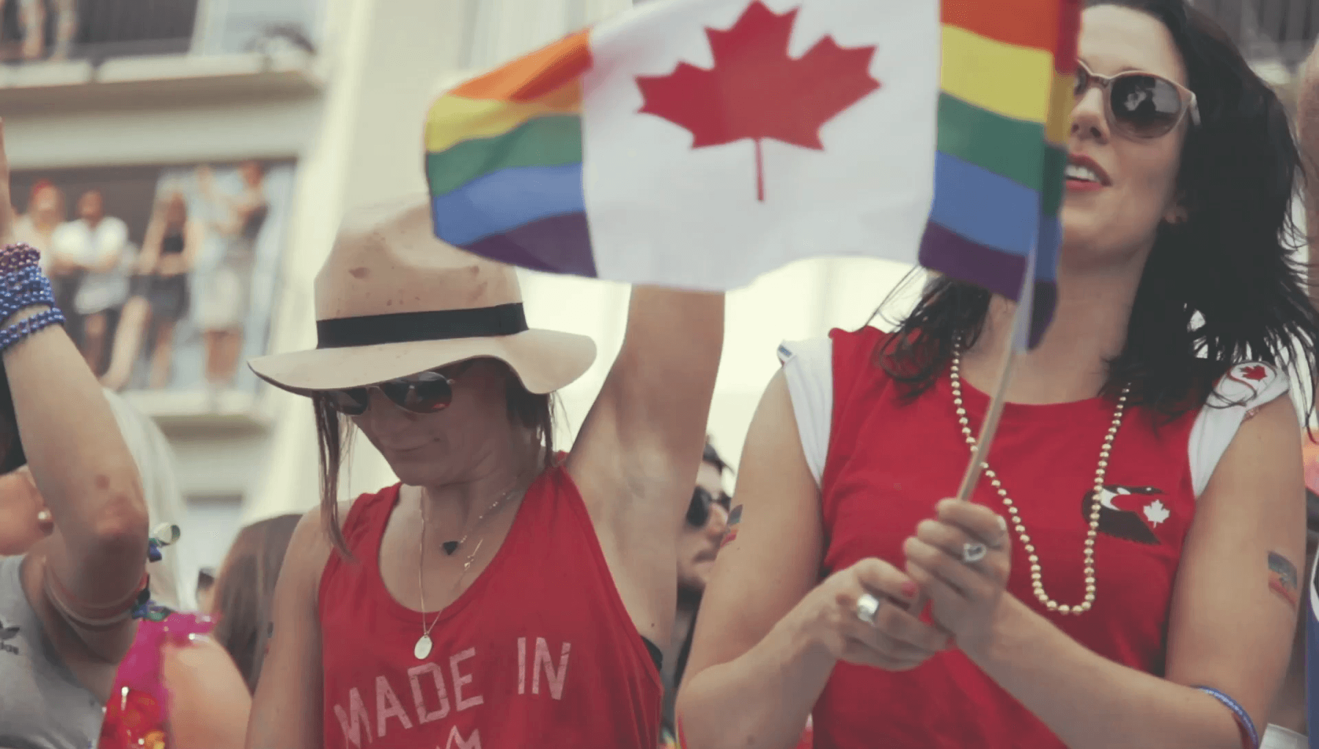 A woman waves a Canadian flag with pride colors