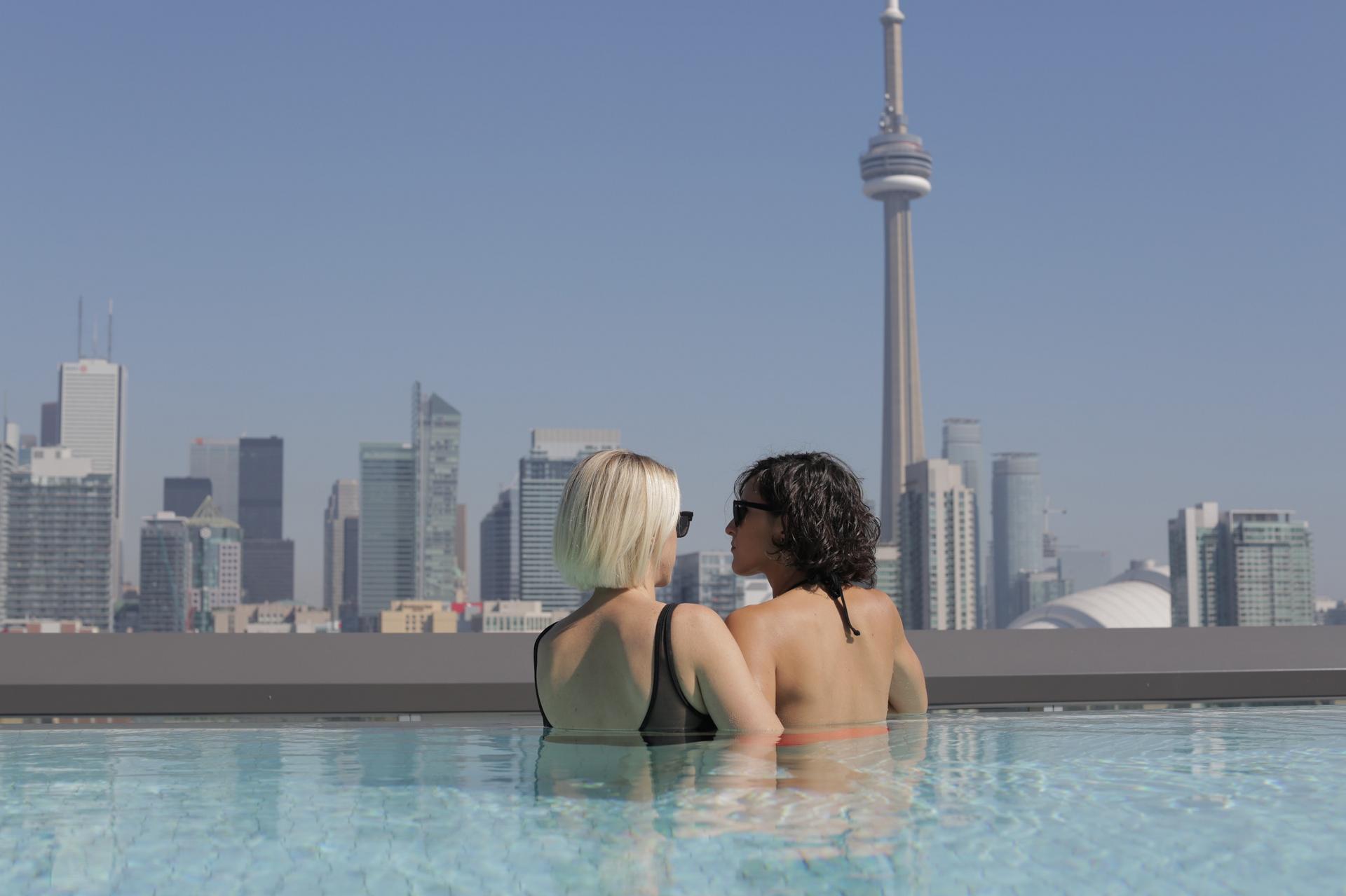 A lesbian couple relaxes in a pool by the CN tower