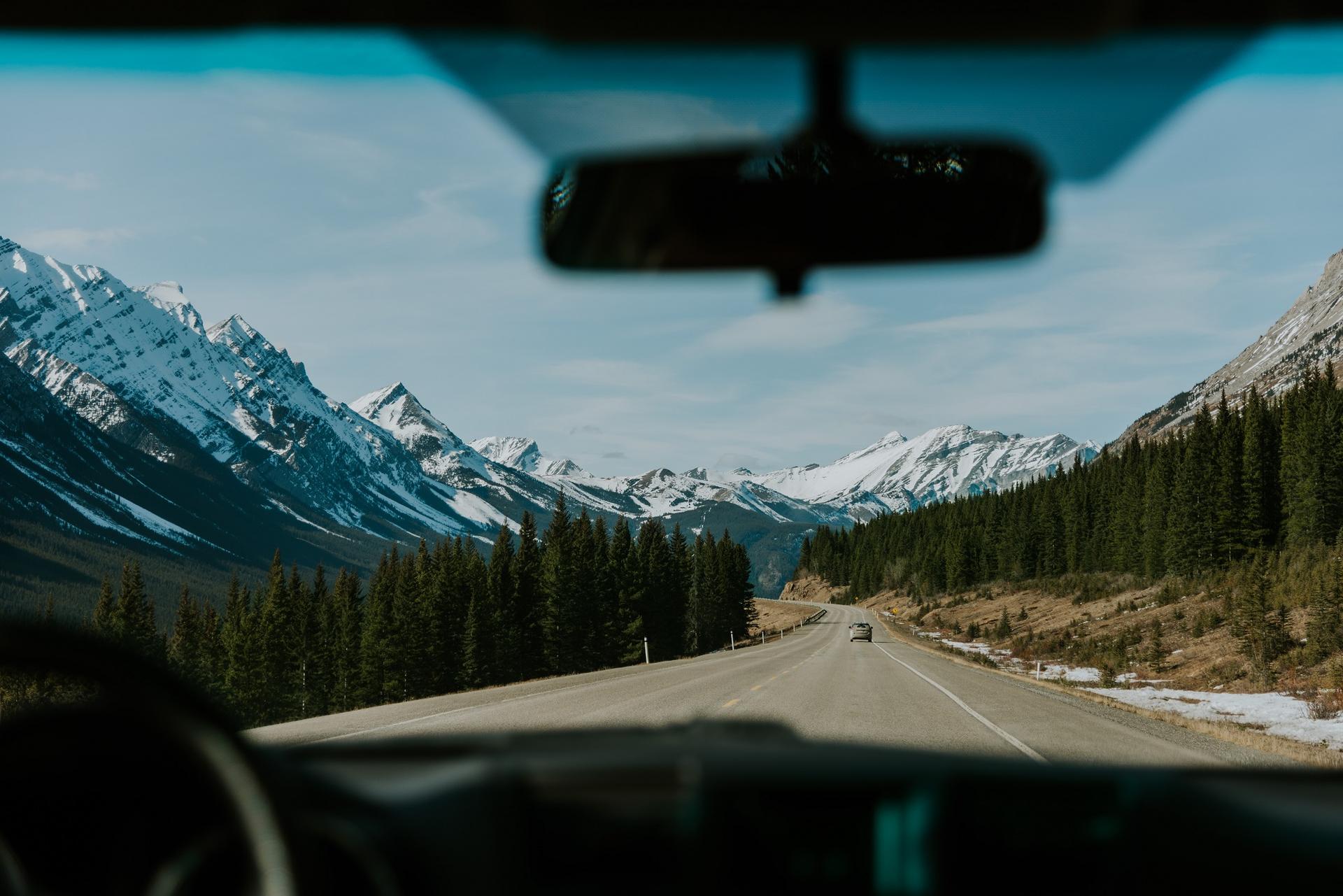 View through the windshield of car driving through the Rocky Mountains in Alberta