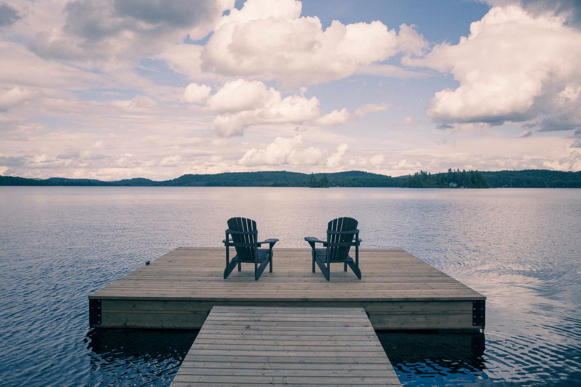 Two wooden lounging chairs on a dock in Muskoka, Ontario