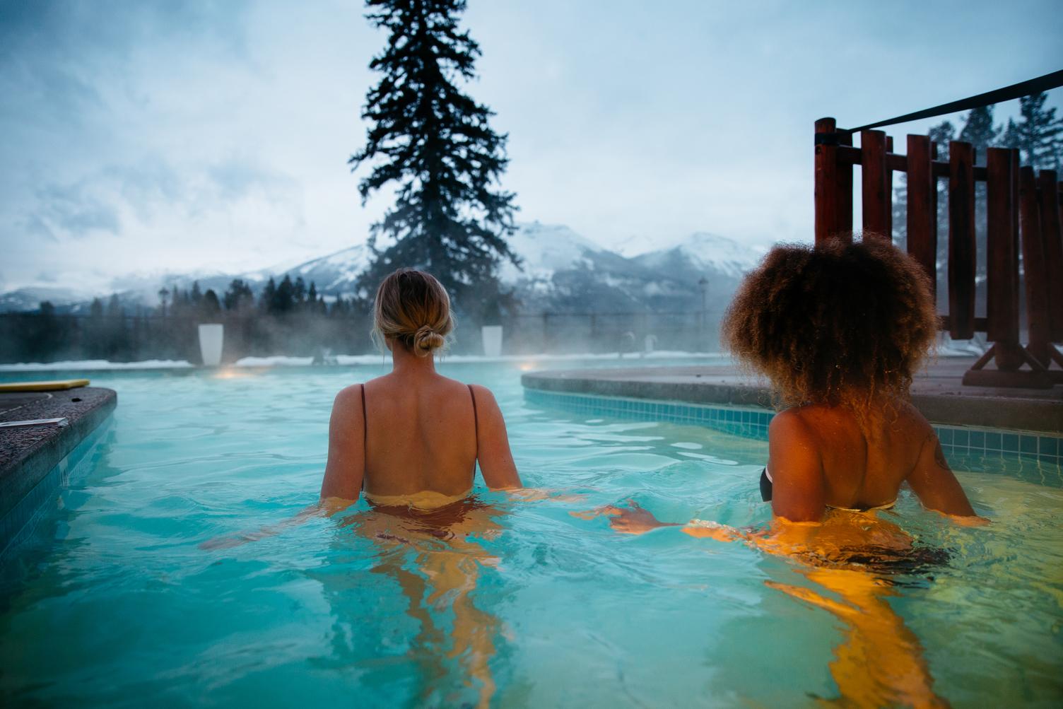 A couple relaxes at a spa in view of the mountains in Jasper