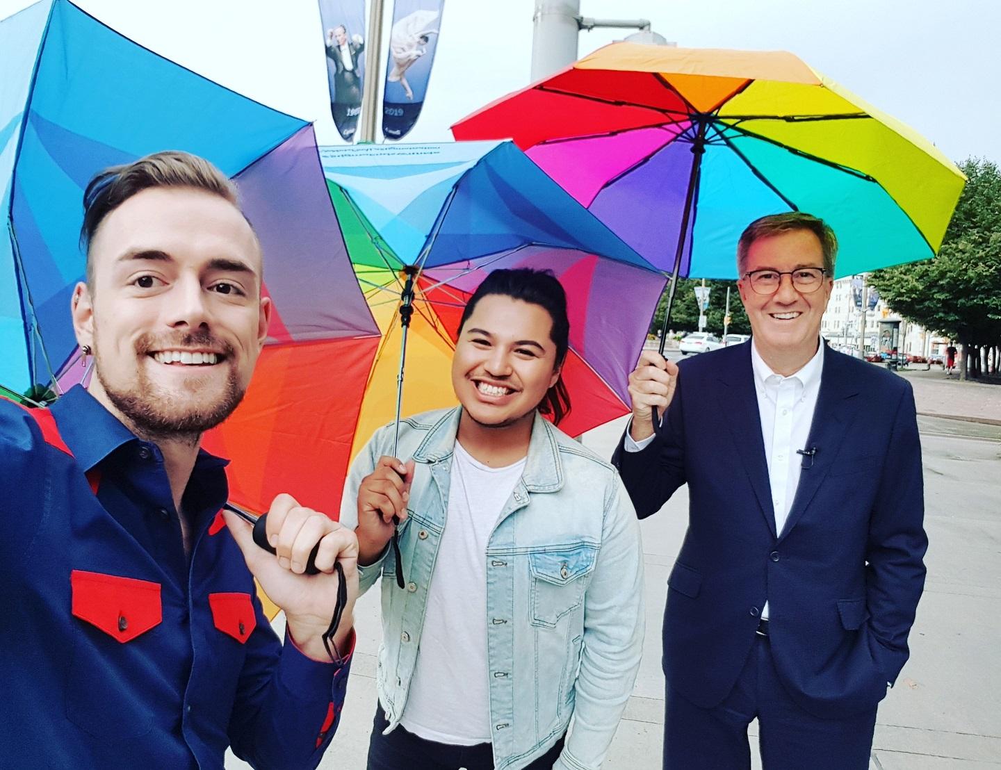 Brett and Cameron hold up rainbow umbrellas