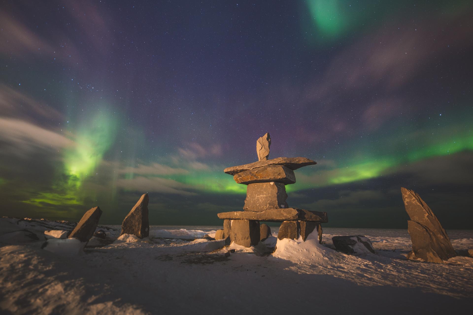 Inukshuk under vibrant northern lights in the winter in Churchill, Manitoba