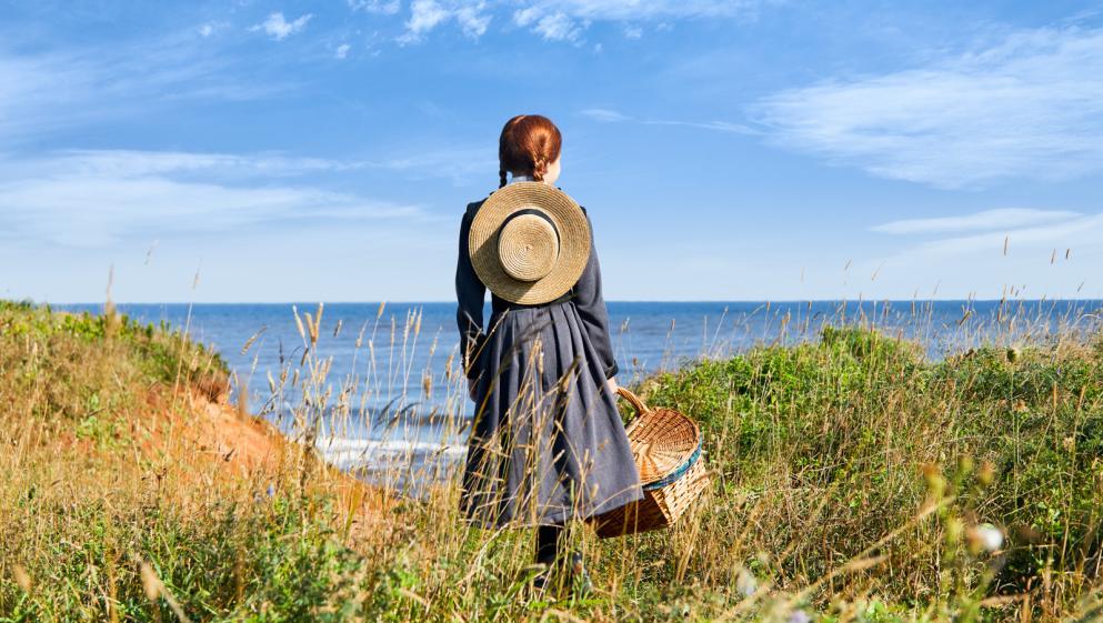 An Anne of Green Gables reenactor looks out on the sea