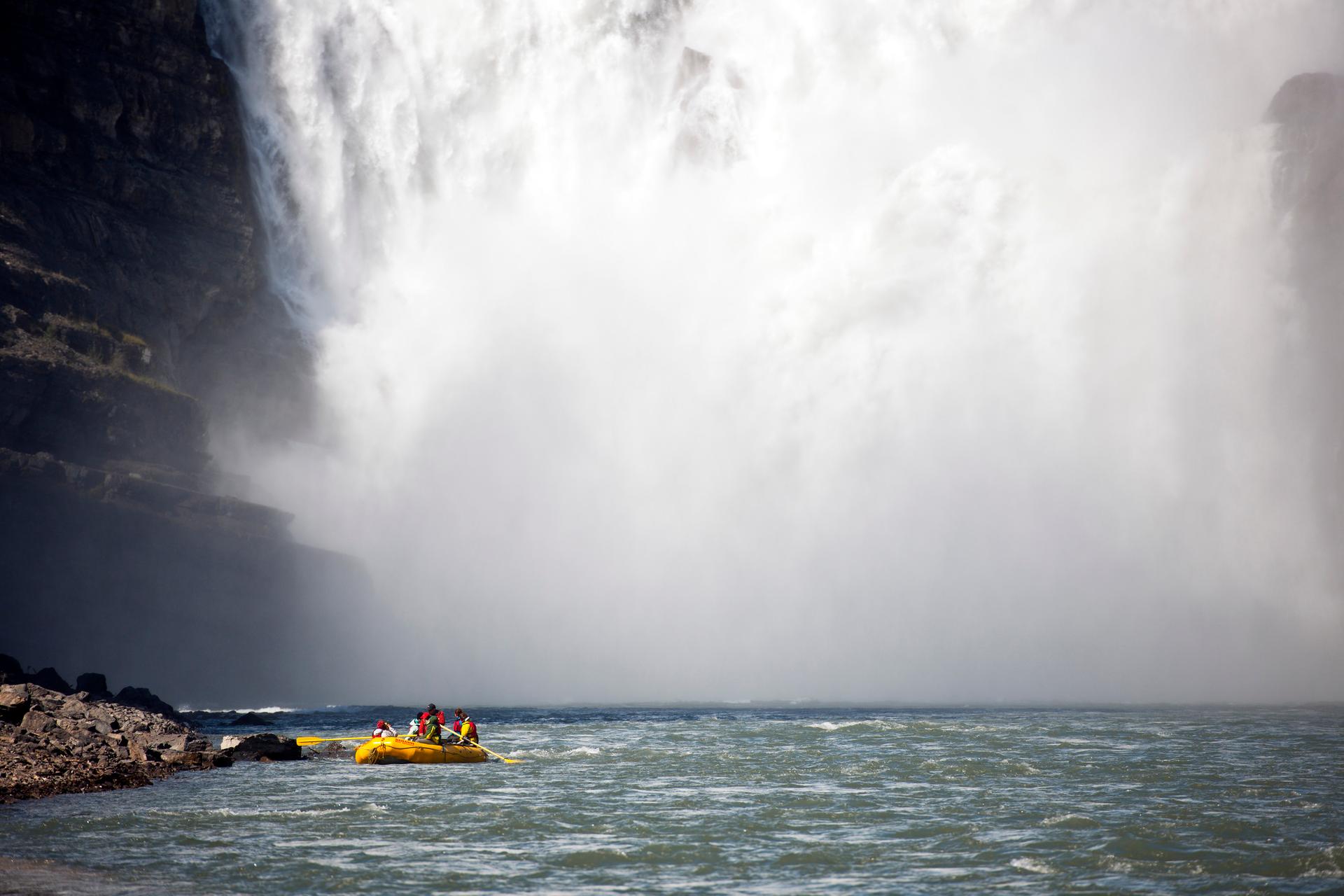 A group paddling a large kayak near a waterfall