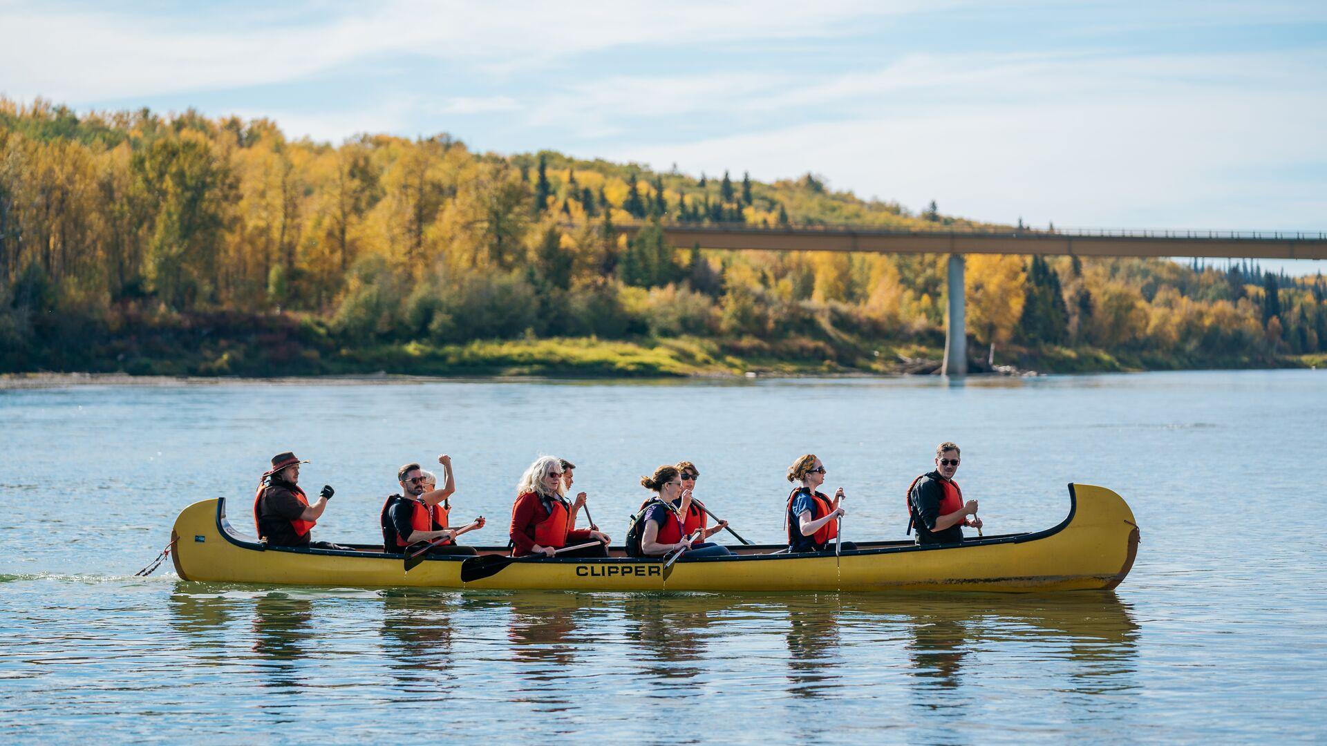 Roadshow finals nine people in canoe on lake with yellow and green trees in the background