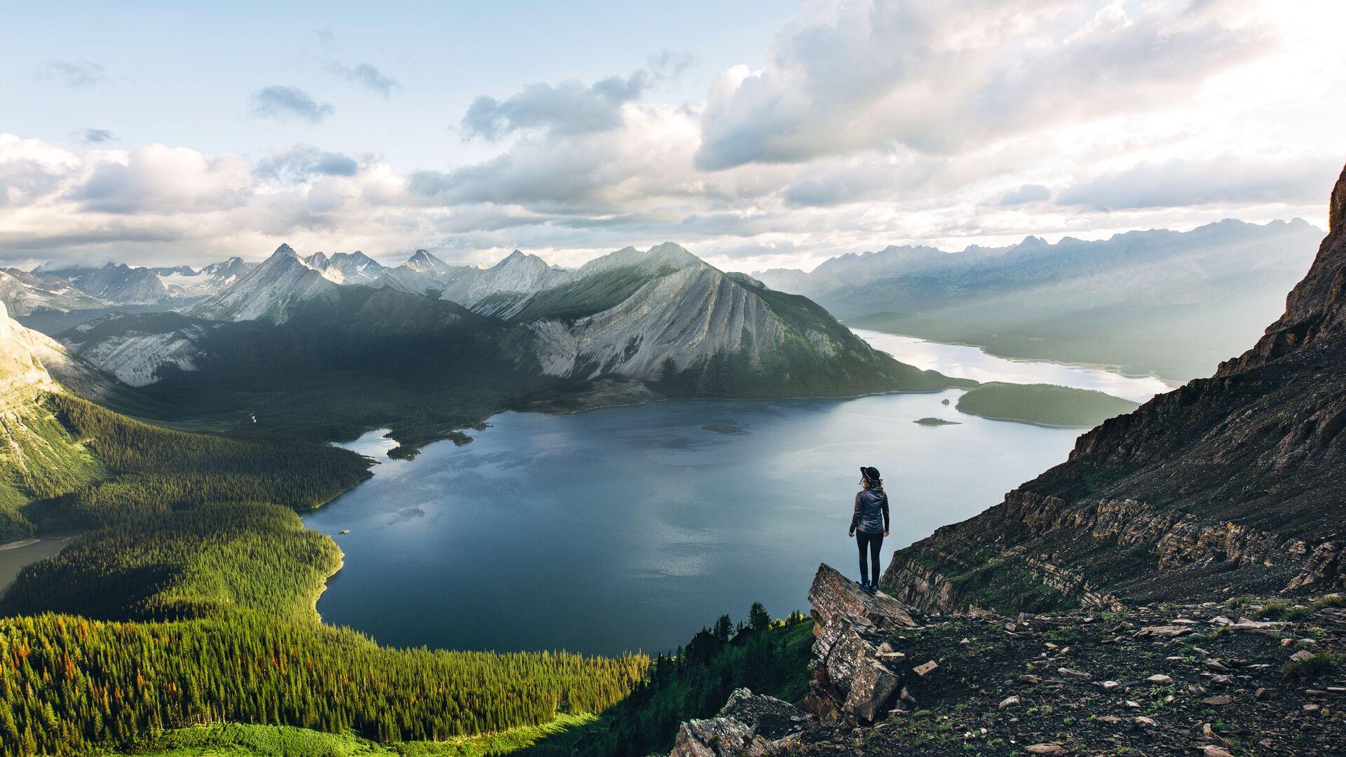 woman standing at the top of a mountain overlooking lake