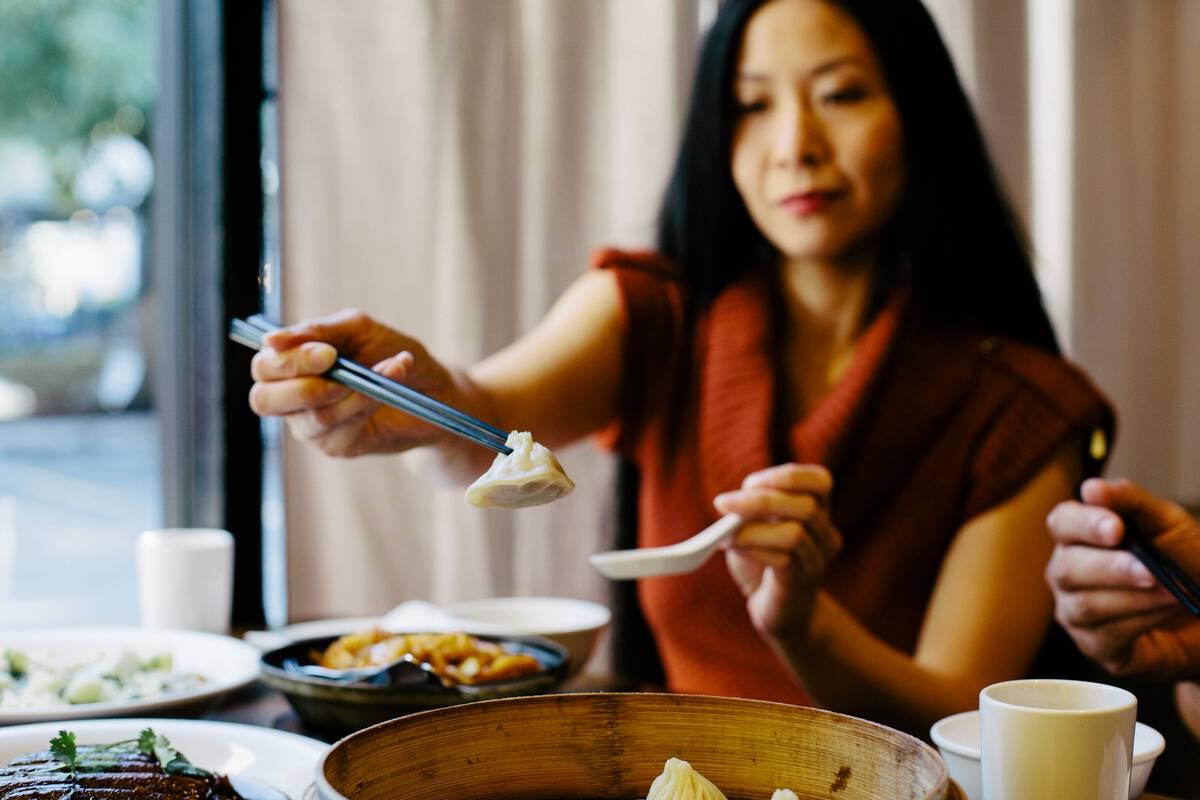 Person holding up a soup dumpling at a restaurant