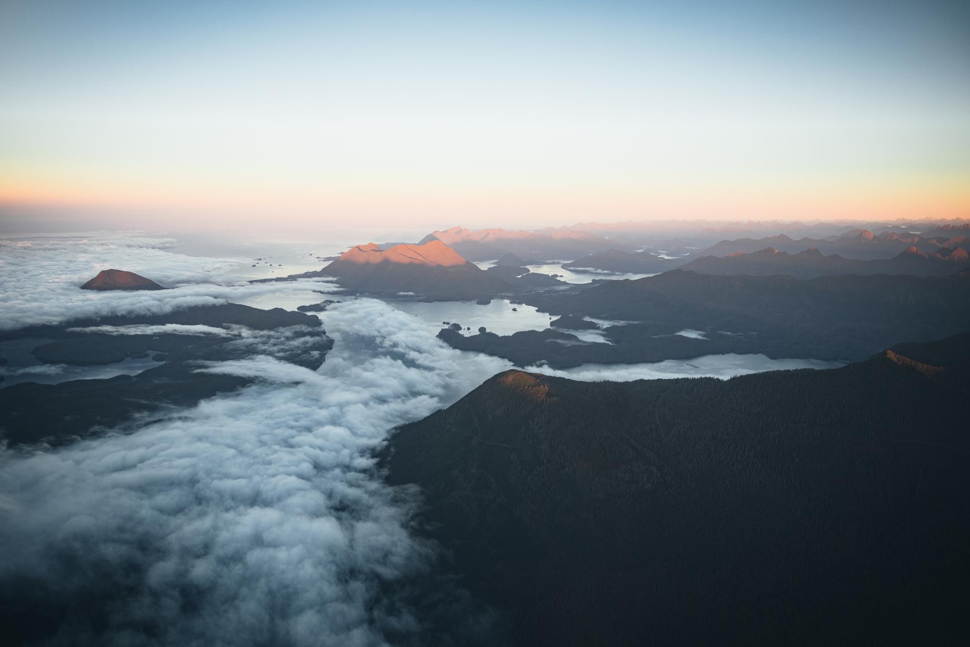 An aerial view of mountains, ocean and clouds.
