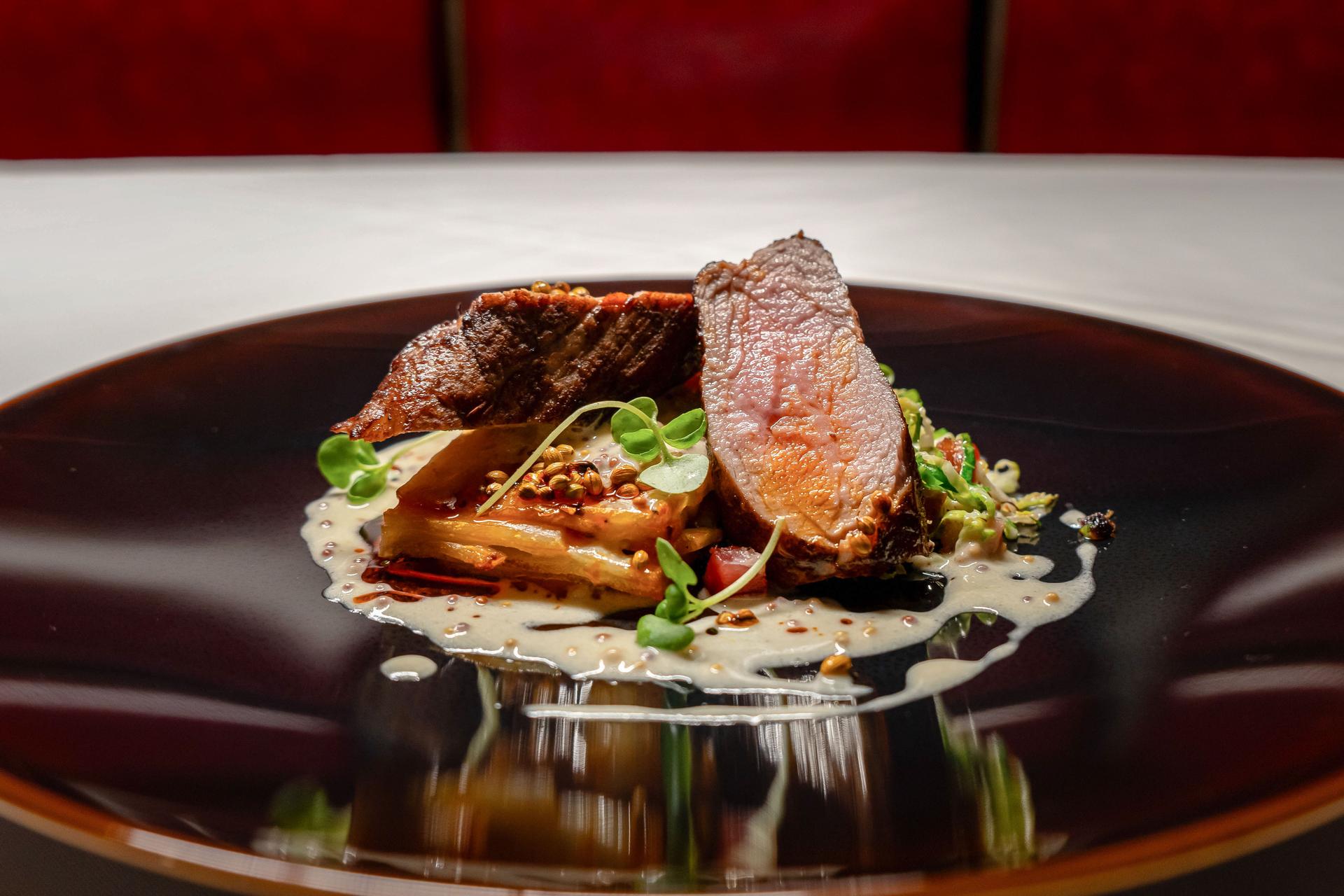 A closeup shot of artistically arranged steak on a plate at a fine-dining restaurant.