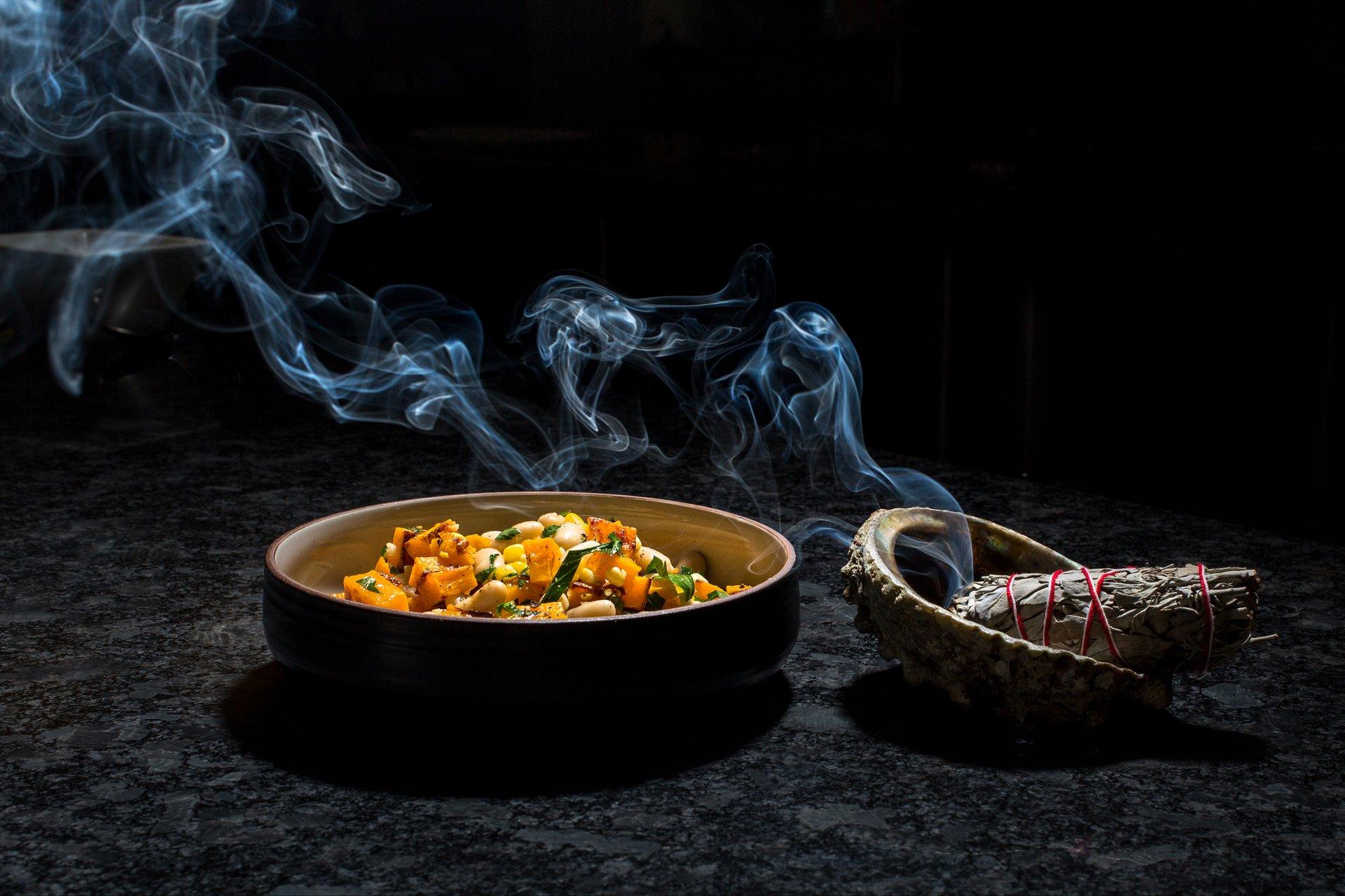 Smoky sage beside a bowl of roasted squash and beans.