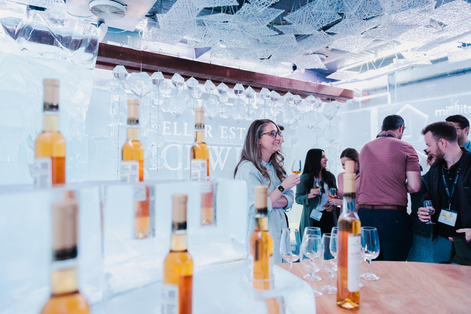 People mingling with wine glasses, a display of icewine in the foreground, at Peller Estates.