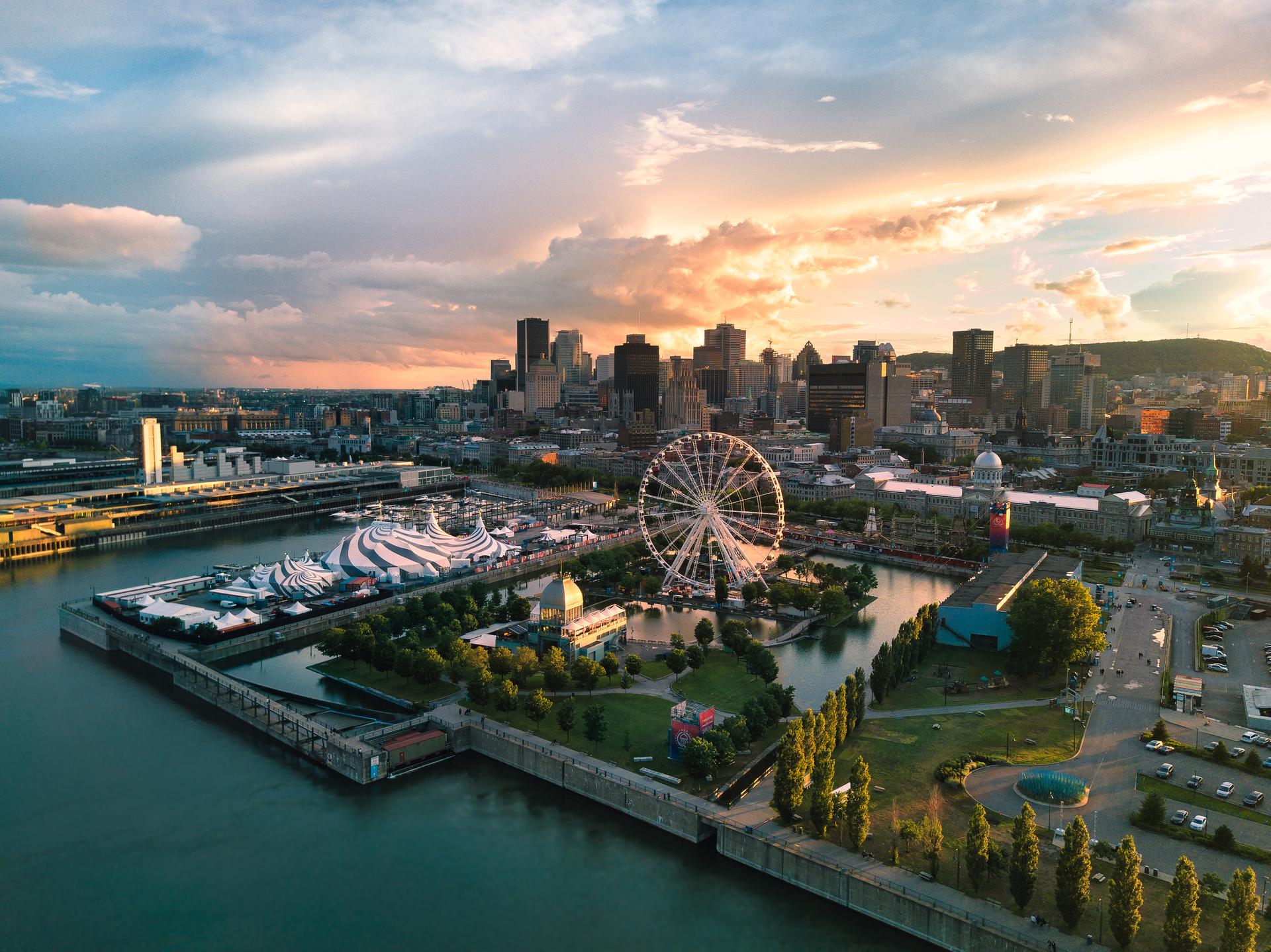 Aerial view of Old Montreal at sunset, showing the Montreal Observation Wheel, Bonsecours Market, and downtown skyline along the St. Lawrence River
