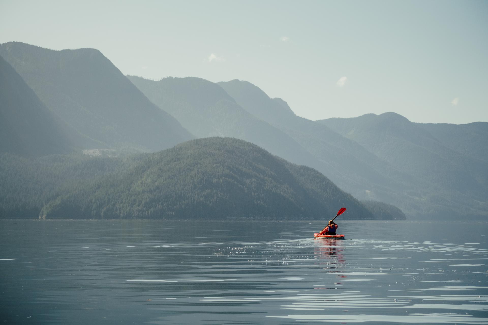 A person kayaking on BC's Sunshine Coast with mountains in the background