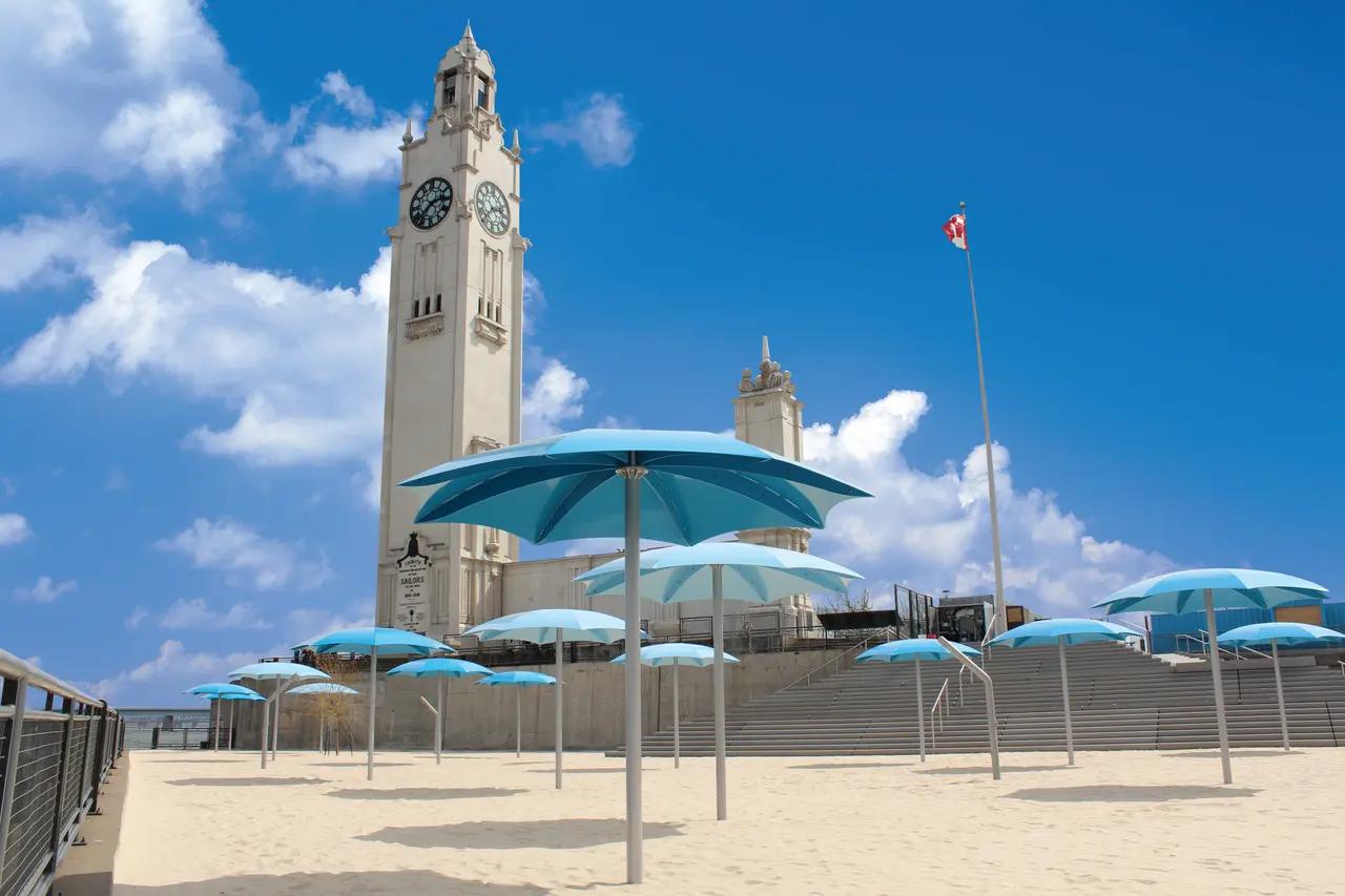 Clock Tower Beach as the ‘urban waterfront without swimming’ example—anchoring the decision-making detail that you come here for sand, views (bridge/Île Sainte‑Hélène), and nearby activities rather than open-water swimming.