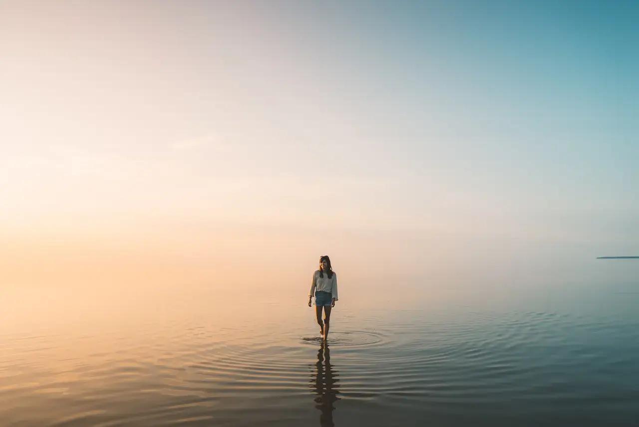A visitor walks across Grand Beach’s sugary white sand with Lake Winnipeg’s calm waters stretching to the horizon—demonstrating how Manitoba’s prairie dunes create a coastal feel on freshwater shores, perfect for families and wind sports enthusiasts.