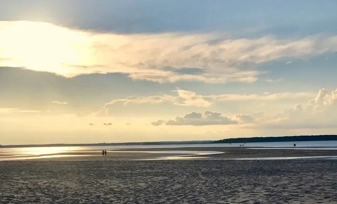 Parlee Beach’s broad sandy expanse meets the Northumberland Strait under dramatic clouds, showcasing the warm shallow waters near Shediac that make this New Brunswick destination consistently rank among Canada’s warmest saltwater swimming spots.