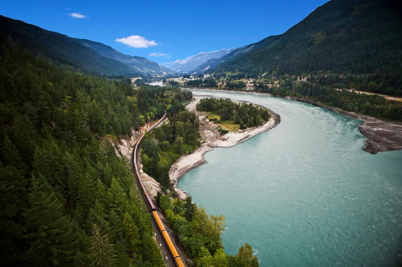 Rocky Mountaineer image supports the ‘adventure without hiking boots’ option, showing how a train journey follows rivers and valleys to deliver water-and-mountain scenery for travellers prioritizing comfort and views.