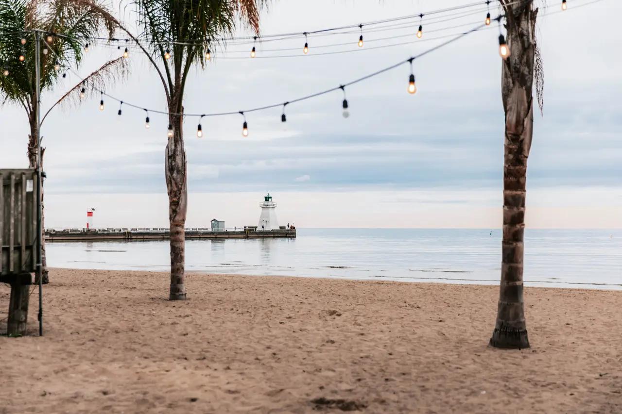 Port Dover section image that adds place-specific cues: pier and lighthouse over calm Lake Erie water—supporting the ‘resort town’ idea and helping readers infer amenities, strolling, and waterfront dining potential.