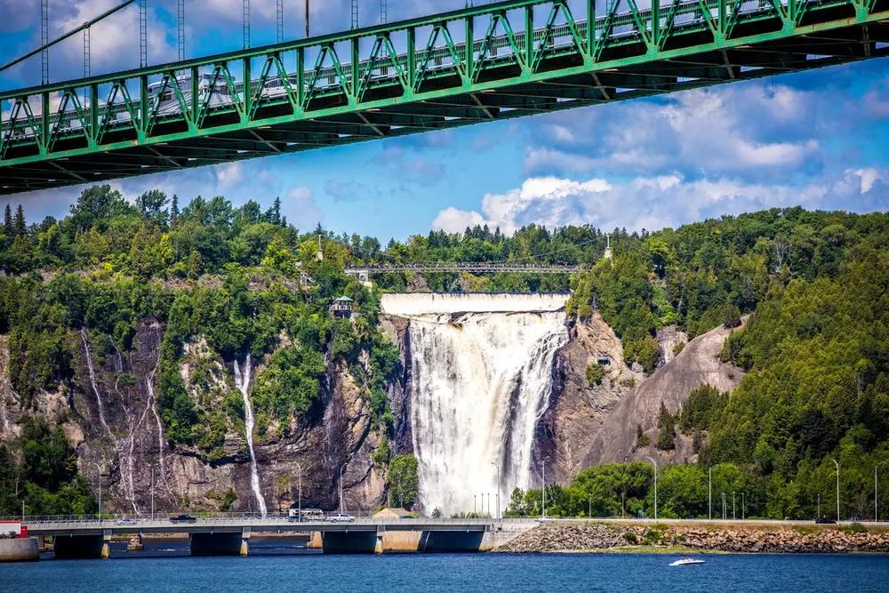 Montmorency Falls near Québec City with its signature suspension bridge spanning above the 83-metre waterfall cascading through lush green forest—the starting point for this Charlevoix road trip itinerary