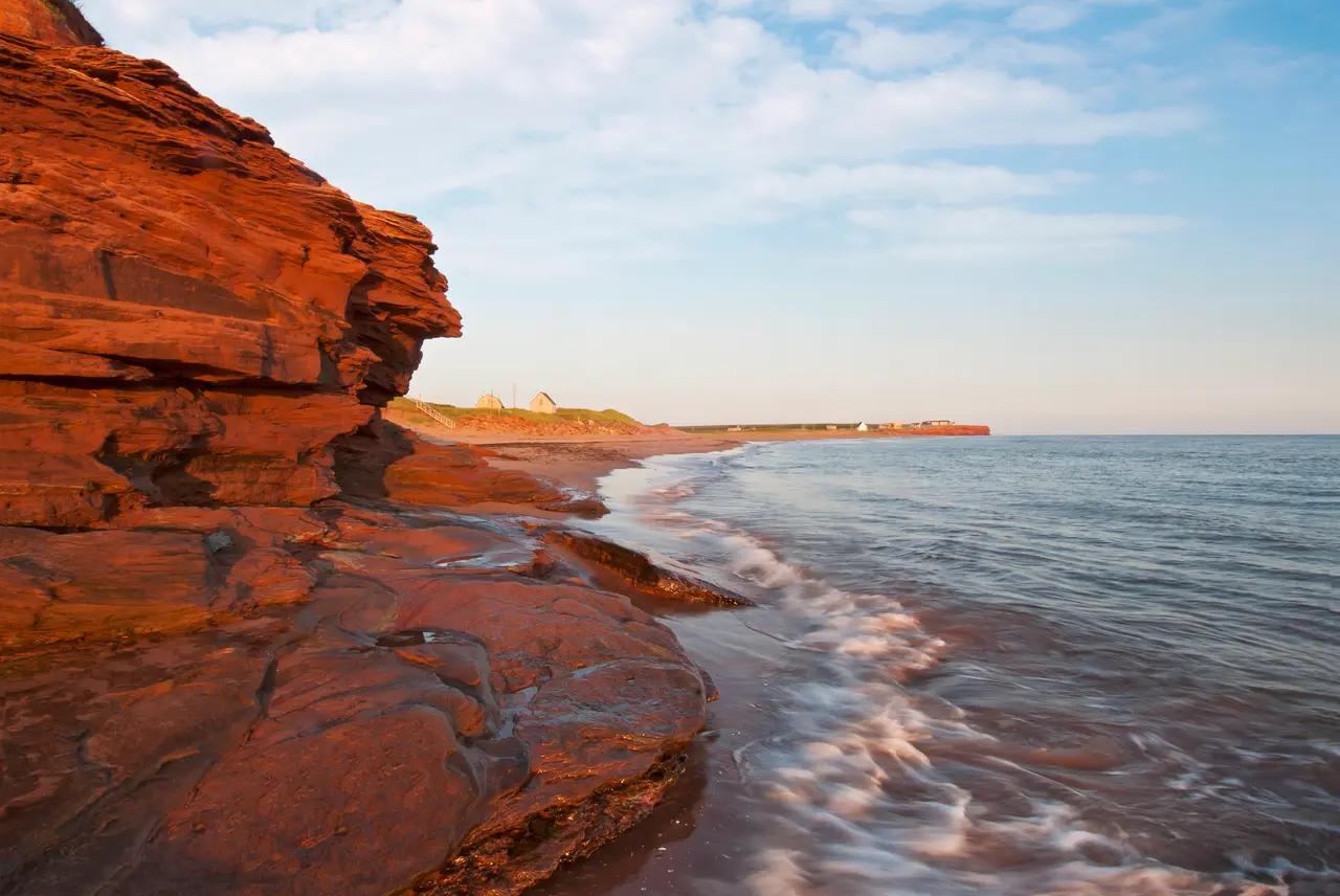 Prince Edward Island’s red sandstone cliffs meeting the shoreline, representing the article’s core itinerary theme: a coastal road trip built around beach landscapes, changing tides, and scenic shoreline drives.