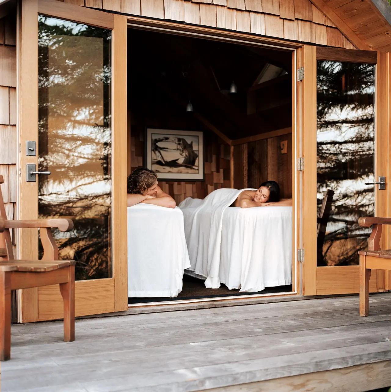 A couple relaxes side by side on massage tables inside a cedar treatment room at the Ancient Cedars Spa.